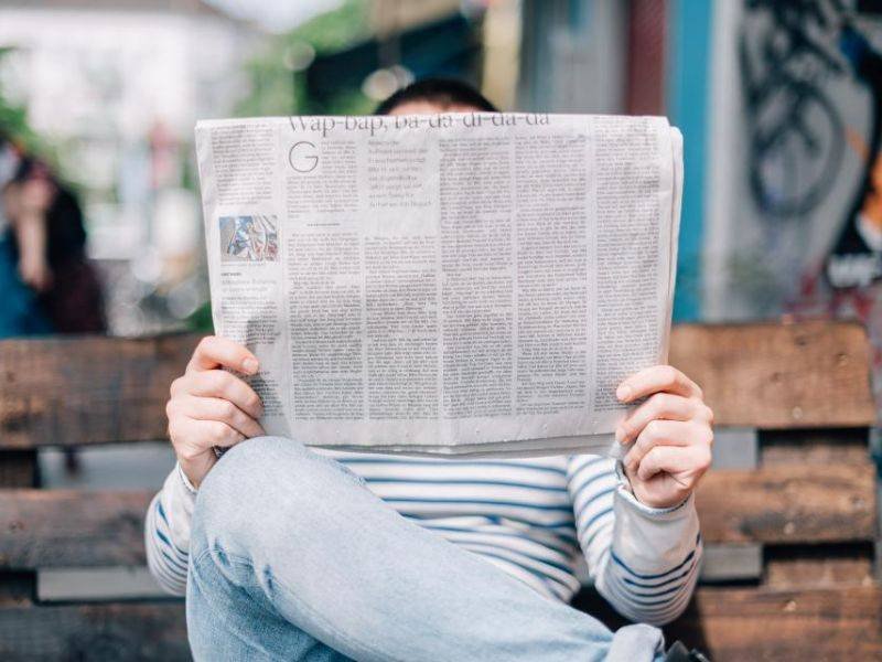 Reading the news on a laptop and paper