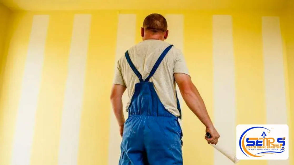 General Liability Insurance for Small Business: Coverage, Cost and How to Buy 1 Painter in blue overalls holding a paint roller in front of a striped yellow wall